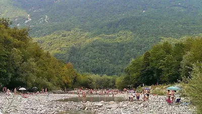 a group of people standing on a rocky beach at Apartment Honey Bee with SAUNA in Kobarid