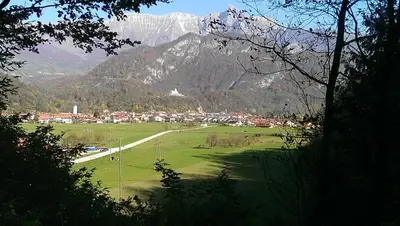 a green field with a town and mountains in the background at Apartment Honey Bee with SAUNA in Kobarid