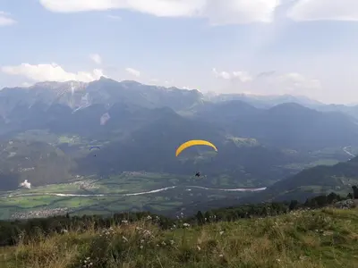a person flying a parachute on top of a mountain at Apartment Honey Bee with SAUNA in Kobarid