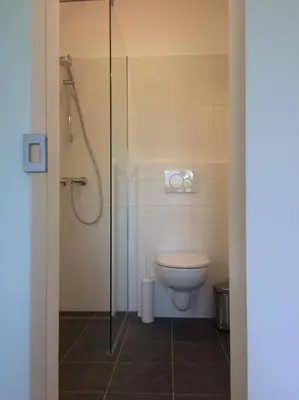 a bathroom with a toilet and a glass shower at Guest House Vitaja in Bled