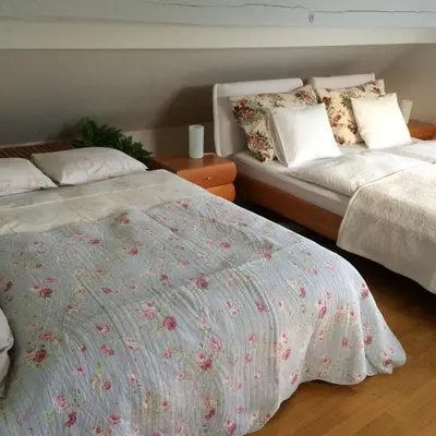a bedroom with two beds with white sheets and flowers at Guest House Vitaja in Bled