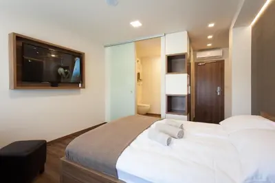 a bedroom with a large bed with a tv on the wall at Hotel Pomaranča in Ptuj