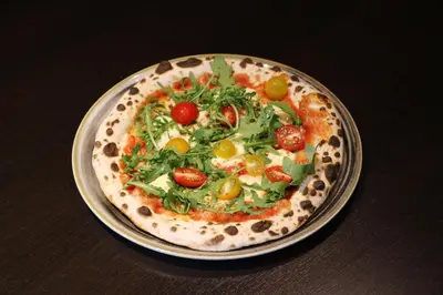 a pizza on a plate on a table at Hotel Pomaranča in Ptuj