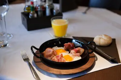 a bowl of breakfast food on a table with a glass of orange juice at Hotel Pomaranča in Ptuj