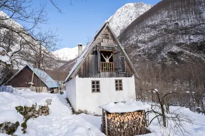 a house in the snow with a mountain in the background at Bezgova Hišica in Bovec