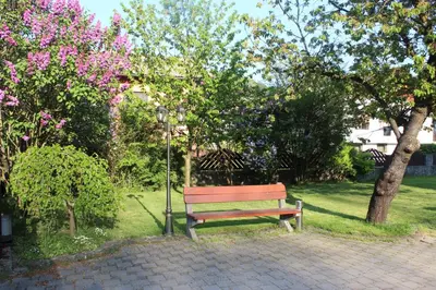a park bench in a park with trees and flowers at Vila Weekend in Rogaška Slatina