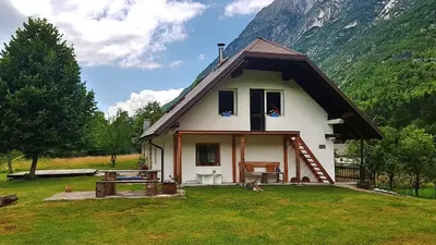 a small white house with a mountain in the background at Bovec Home At Three Samoyeds in Soča