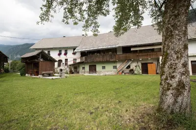a large house with a green field in front of it at Turistična kmetija Gartner in Bohinj