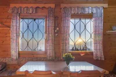 a dining room with a table and two windows at Chalet Resa - Velika planina in Stahovica