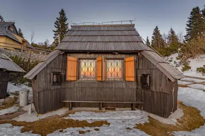 a small wooden house with a bench in the snow at Chalet Resa - Velika planina in Stahovica