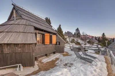a wooden building with a bench in the snow at Chalet Resa - Velika planina in Stahovica