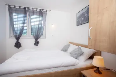 a bedroom with a bed with white sheets and a window at Apartments Razingar 9 in Bled
