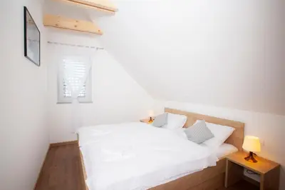 a white bedroom with a bed and a window at Apartments Razingar 9 in Bled