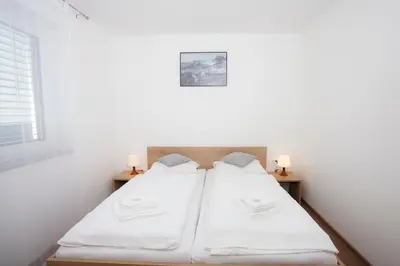 two beds in a room with white walls and two candles at Apartments Razingar 9 in Bled