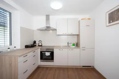 a white kitchen with white cabinets and a sink at Apartments Razingar 9 in Bled