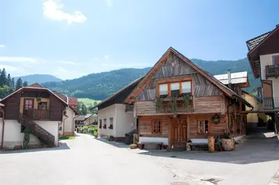 a group of wooden buildings in a street at Juvanova hiša - Apartments and Rooms in Luče