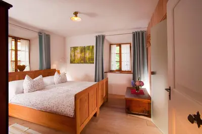 a bedroom with a bed with a wooden frame and windows at Juvanova hiša - Apartments and Rooms in Luče