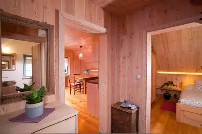 a room with wooden walls and a bedroom with a bed at Juvanova hiša - Apartments and Rooms in Luče