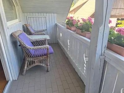 two chairs sitting on a porch with flowers in pots at Apartmaji Marinka Hodnik in Bohinj