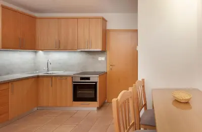 a kitchen with wooden cabinets and a table and a sink at Bungalows Rogla in Zreče