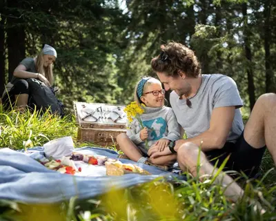 a man and woman sitting on the grass at a picnic at Bungalows Rogla in Zreče