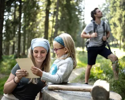 two women sitting on a bench looking at a piece of paper at Bungalows Rogla in Zreče