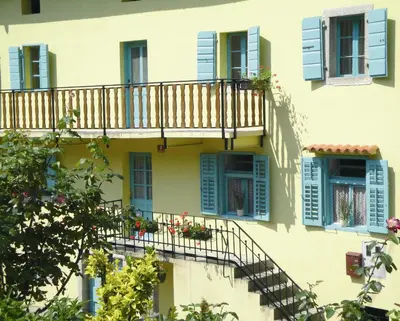 a building with blue shutters and a balcony at Authentic traditional Soca Valley home in Kanal