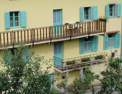 a building with blue windows and balconies with plants at Authentic traditional Soca Valley home in Kanal