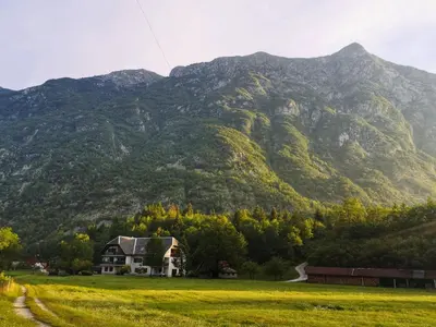 a house in a field with a mountain in the background at Apartment Joži in Soča