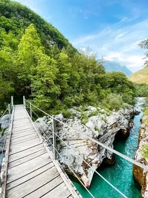 a wooden bridge over a river next to a mountain at Apartment Joži in Soča