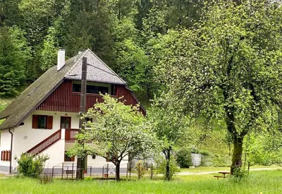 a red and white house in a field with trees at Apartment Joži in Soča