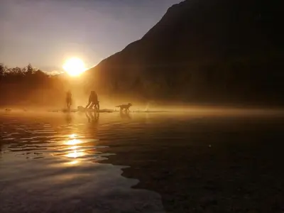 people and a dog walking on the beach at sunset at Apartment Joži in Soča