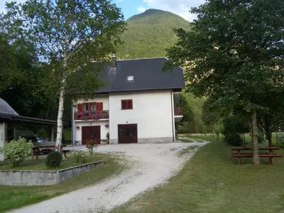 a white house with a mountain in the background at Apartment Joži in Soča
