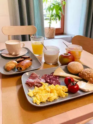 a table with a plate of scrambled eggs and other breakfast foods at Soca Guesthouse in Kanal