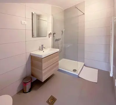 a white bathroom with a sink and a shower at Soca Guesthouse in Kanal