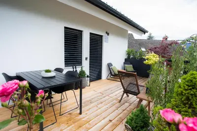 a patio with a black table and chairs on a wooden deck at House 24 Bled in Bled