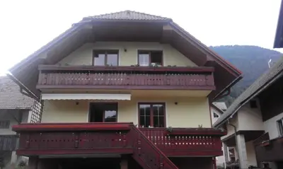 a large house with a red balcony on top of it at Apartment Korošec Matej in Bohinj