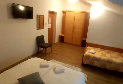 a room with two beds and a chair and a television at Gostišče Jazbec - Idrsko - Kobarid in Kobarid