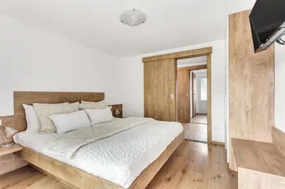 a white bedroom with a large bed and a flat screen tv at Apartments Svetina in Bled