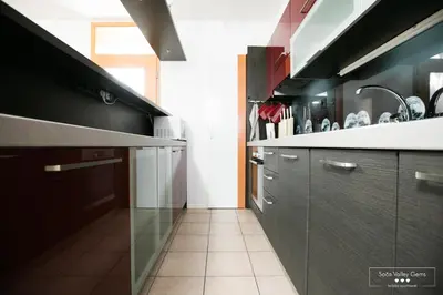 a kitchen with black cabinets and a tile floor at Luxurious RUBY Apartment with SAUNA in Kobarid