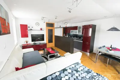a living room with a white couch and a kitchen at Luxurious RUBY Apartment with SAUNA in Kobarid