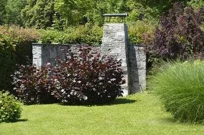 a garden with a stone wall and a bush with flowers at Vila Laura in Bled
