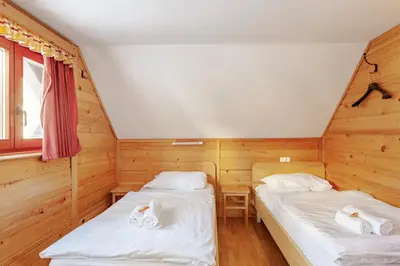 two beds in a room with wooden walls at Chalet Pokljuka in Goreljek