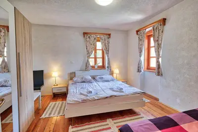 a bedroom with a bed and a television and two windows at Jacobs Resort House Planica in Kranjska Gora