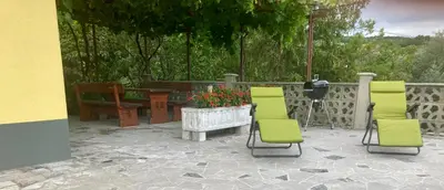 a patio with two chairs and a table and a bench at First Vrtovin Apartment in Črniče