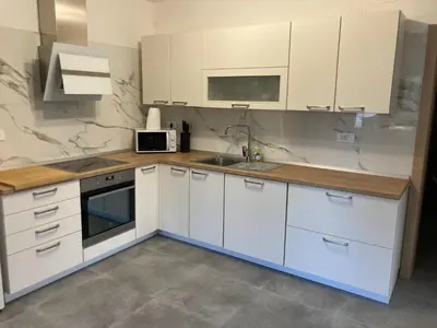 a kitchen with white cabinets and a sink and a microwave at First Vrtovin Apartment in Črniče