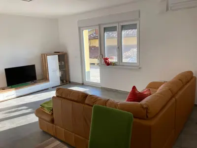 a living room with a brown couch and a tv at First Vrtovin Apartment in Črniče