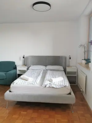 a large bed in a bedroom with a blue couch at Dunajska Apartment in Ljubljana