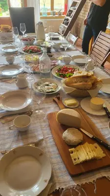 a wooden table with plates of food and wine glasses at Mala Kmetija in Slovenske Konjice