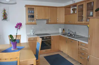 a kitchen with wooden cabinets and a sink and a table at Apartma Maržič in Kranjska Gora